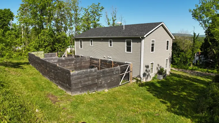 Drone view of the property exterior and wooded setting