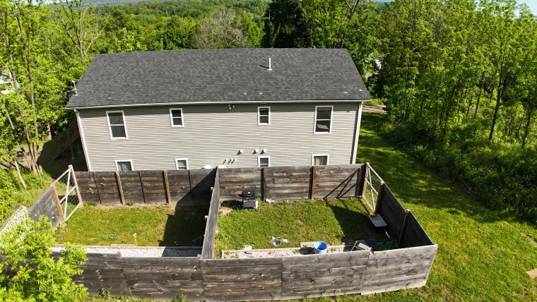 Drone perspective showing the house, yard, and hillside backdrop